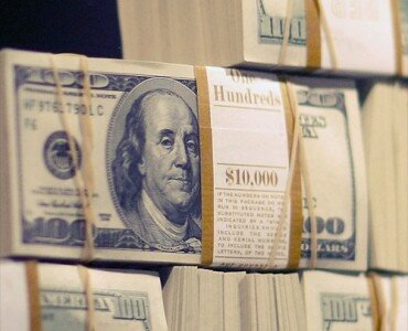 Stacked bundles of hundred-dollar bills banded with ,000 straps and rubber bands