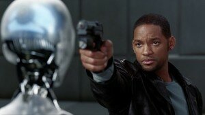 Will Smith in a black jacket aims a handgun at a silver humanoid robot from I, Robot