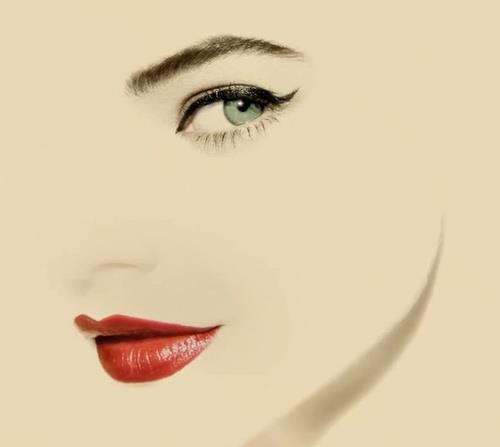 Minimalist face graphic with one green eye, winged eyeliner, and bright red lipstick on cream