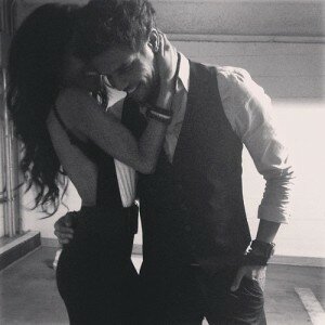Grainy black-and-white embrace of a smiling man in a vest holding a woman in a backless dress
