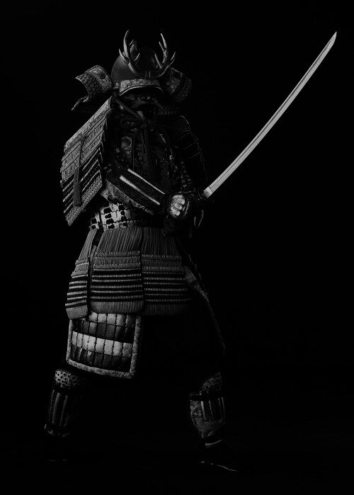 Full samurai armor with antlered helmet, warrior holding a raised katana against black