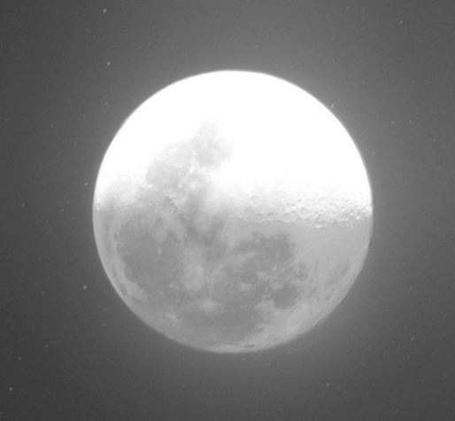 Full moon centered in a dark grainy night sky, bright upper half and cratered lower half