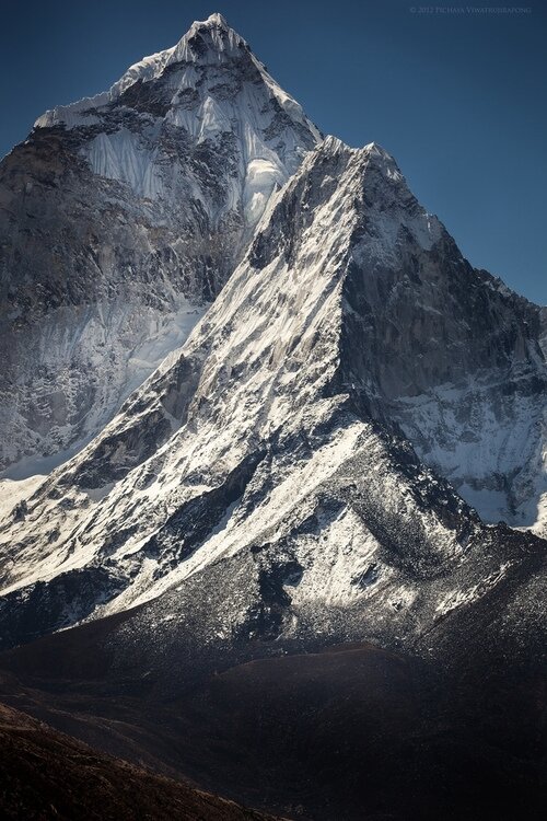 Sharp snow-patched mountain peak with a razor ridge against a clear dark navy sky